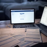 Close-up of student loan debt documents and bills stacked on desk next to laptop showing tuition pay